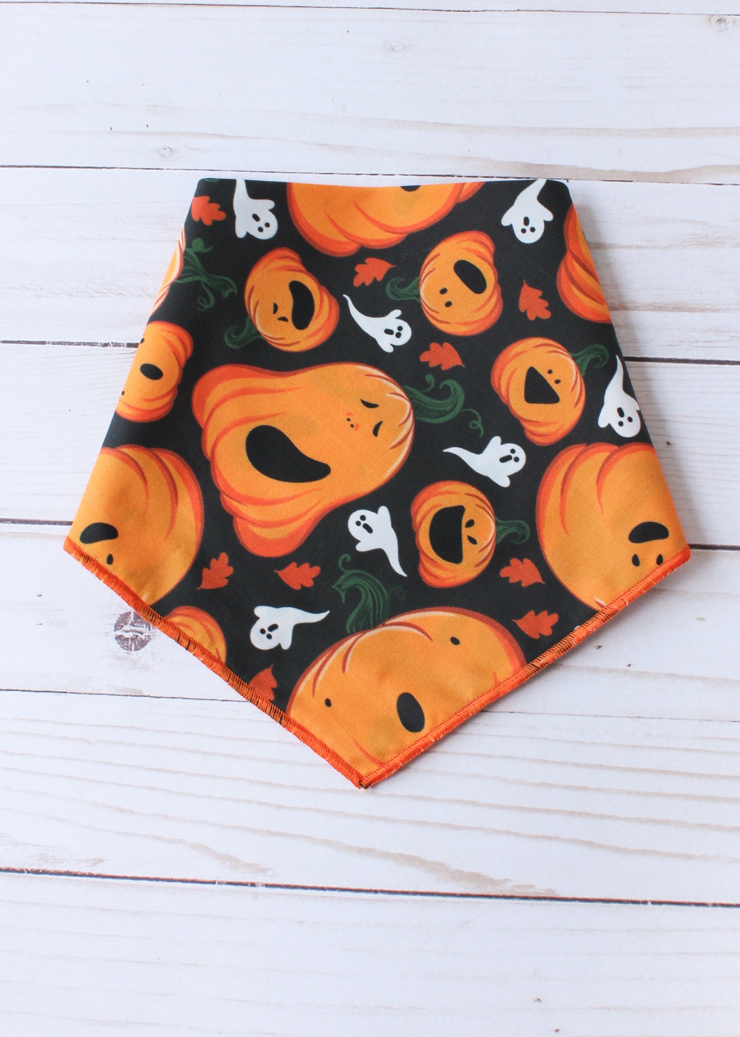 Halloween-themed bandana with pumpkins and ghosts on a wooden surface