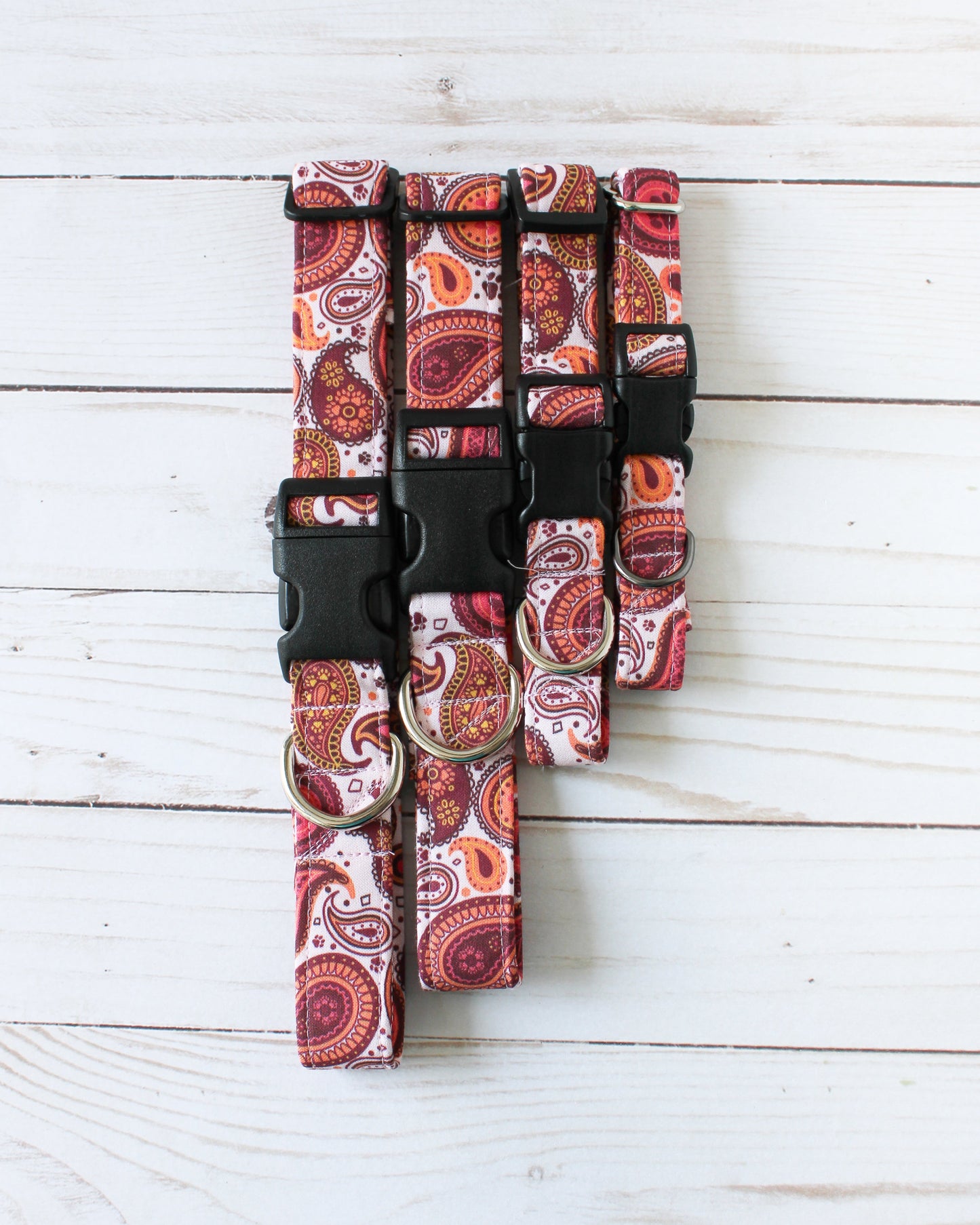 Set of red paisley-patterned Collars on a white wooden surface