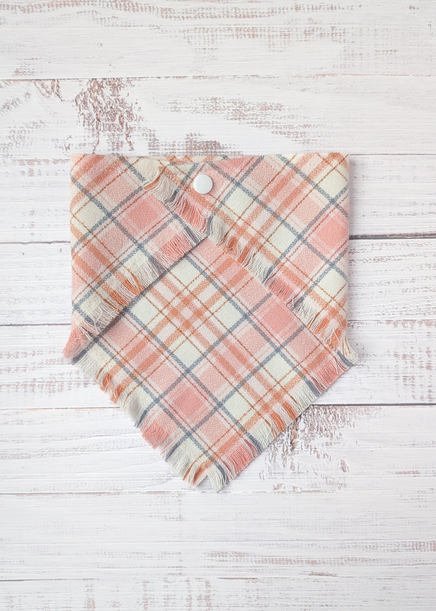Plaid flannel bandana  with pink and light gray pattern on a wooden surface