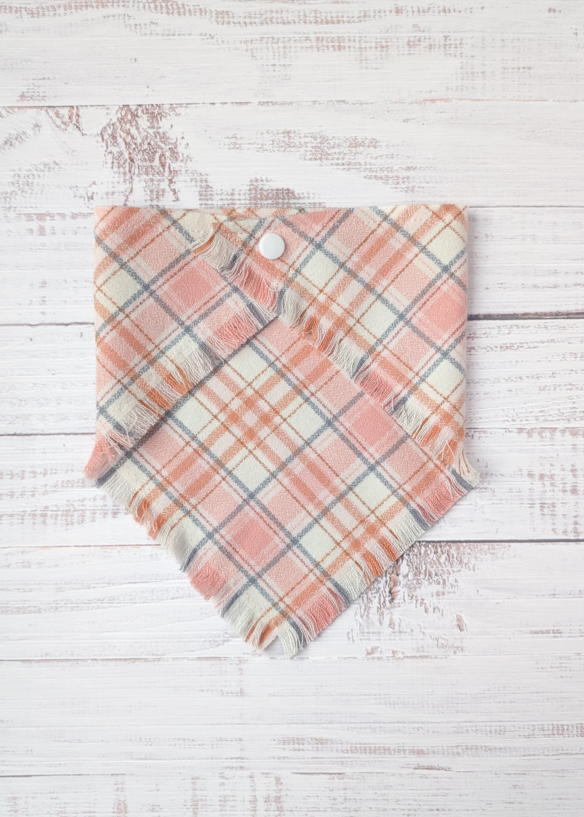 Plaid flannel bandana  with pink and light gray pattern on a wooden surface