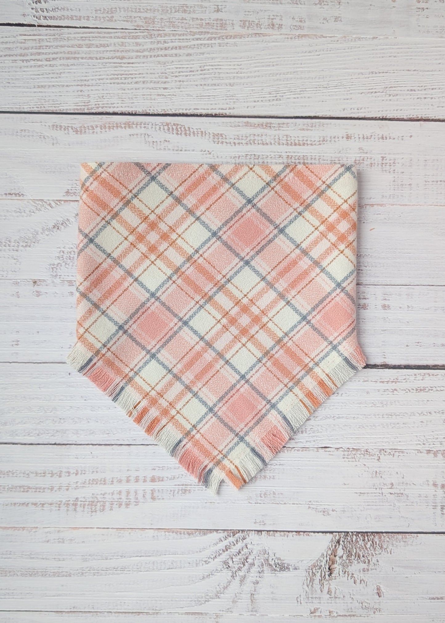 Plaid flannel bandana  with pink and light gray pattern on a wooden surface