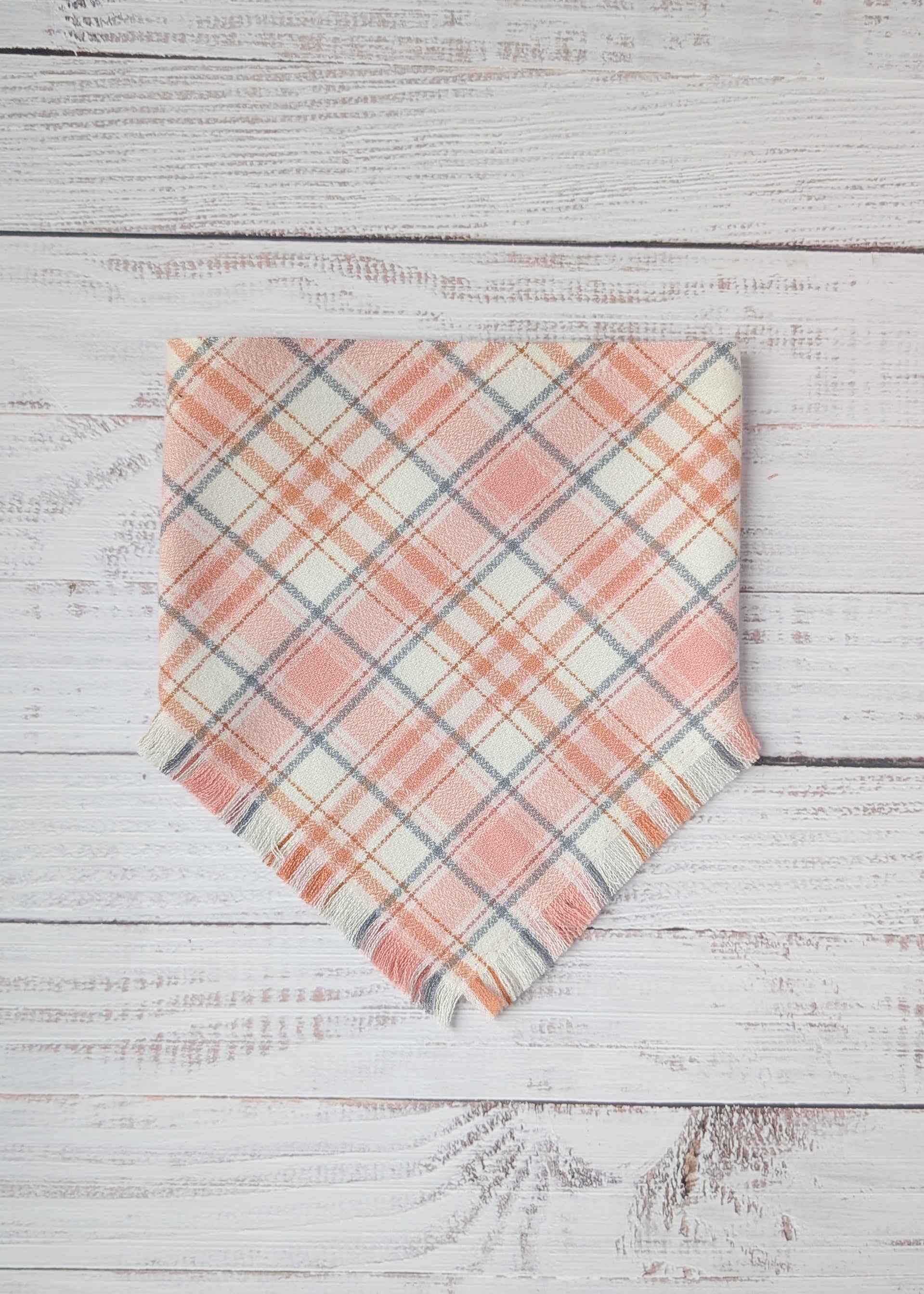 Plaid flannel bandana  with pink and light gray pattern on a wooden surface