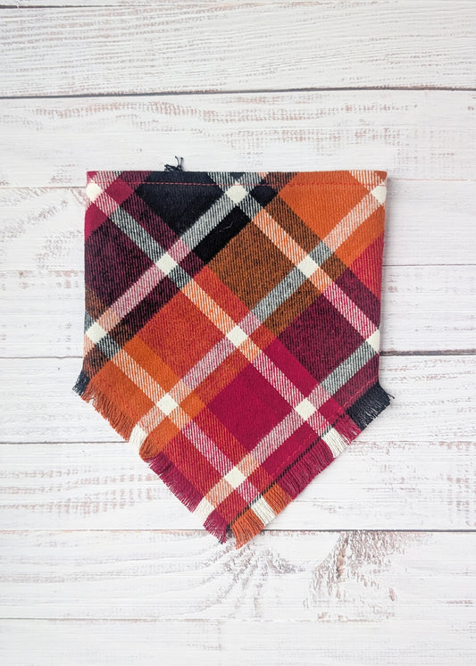 Plaid Flannel Bandna with maroon, black, orange, white plaid pattern on a wooden surface