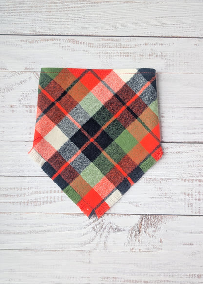 Green, Black, white, and orange plaid flannel bandana on a wooden background