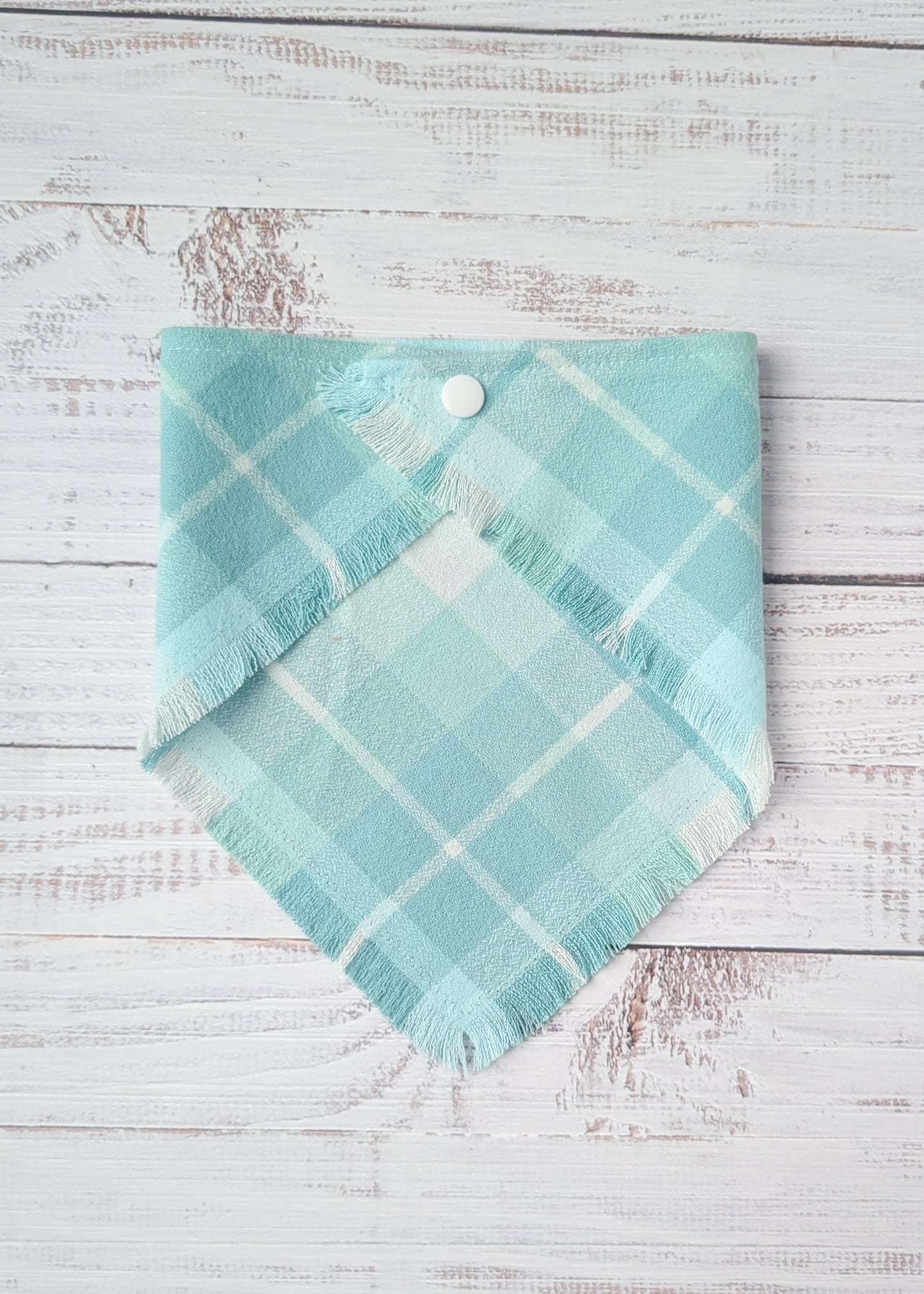 Turquoise plaid flannel bandana on a wooden surface