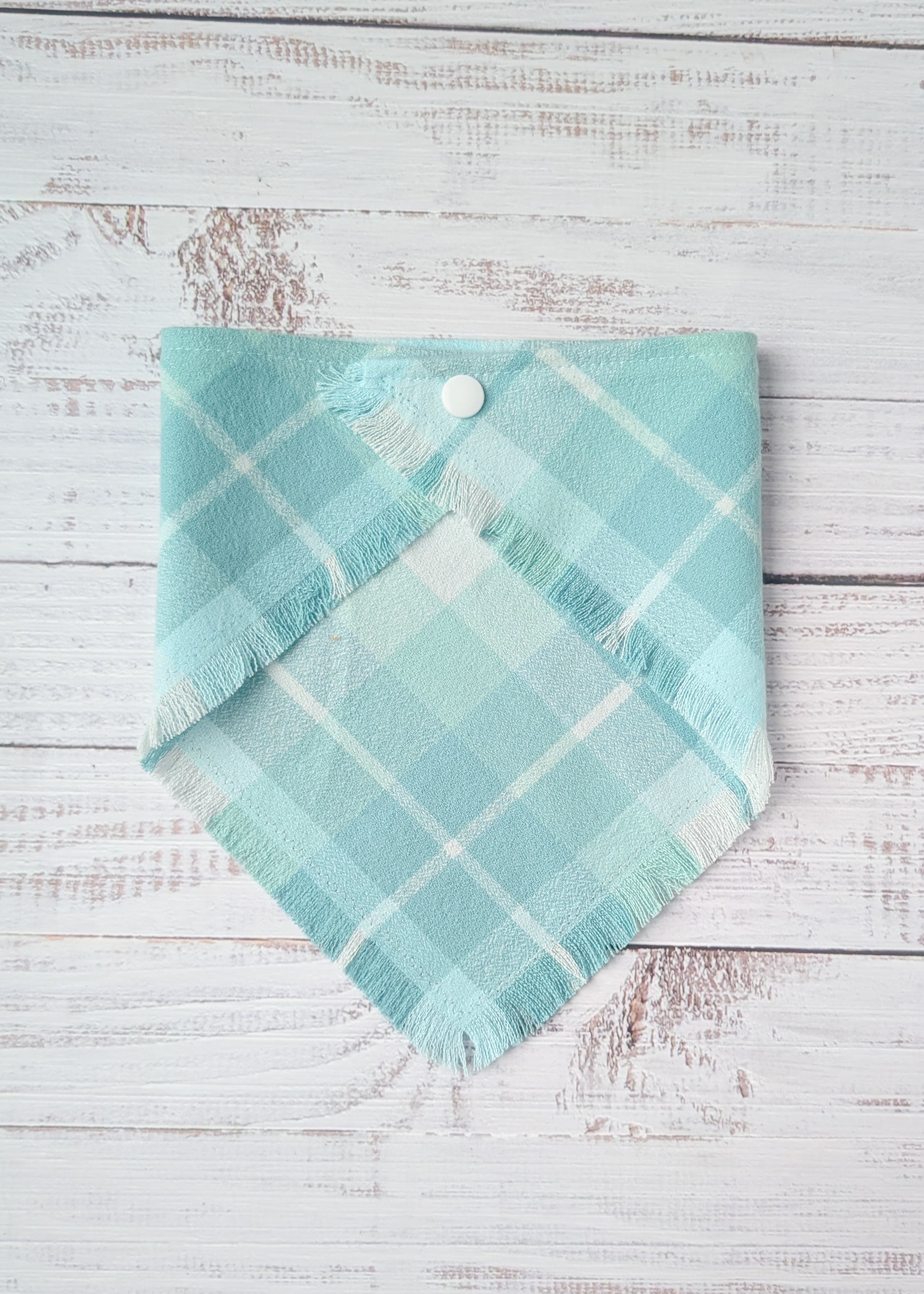 Turquoise plaid flannel bandana on a wooden surface