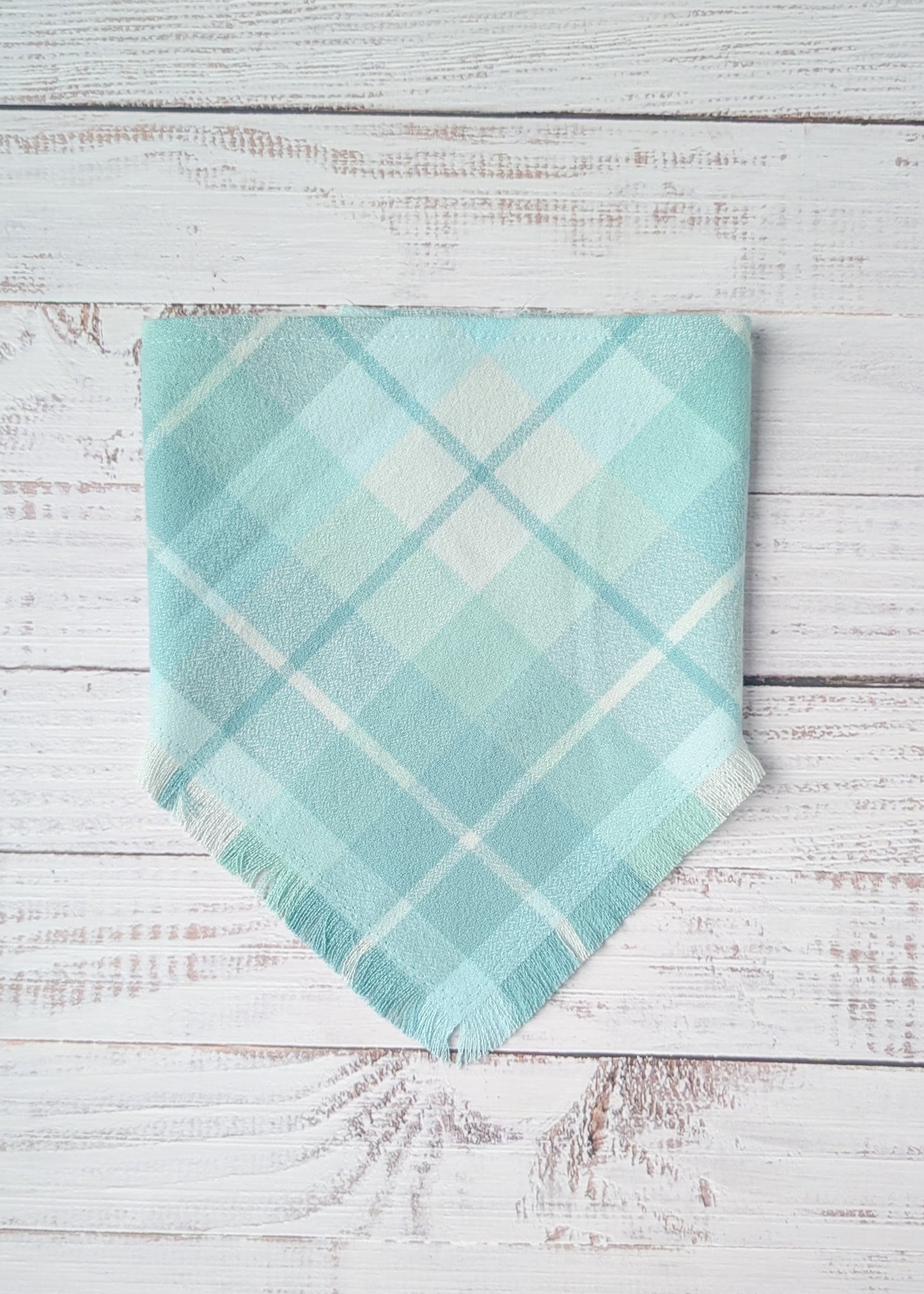 Turquoise plaid flannel bandana on a wooden surface