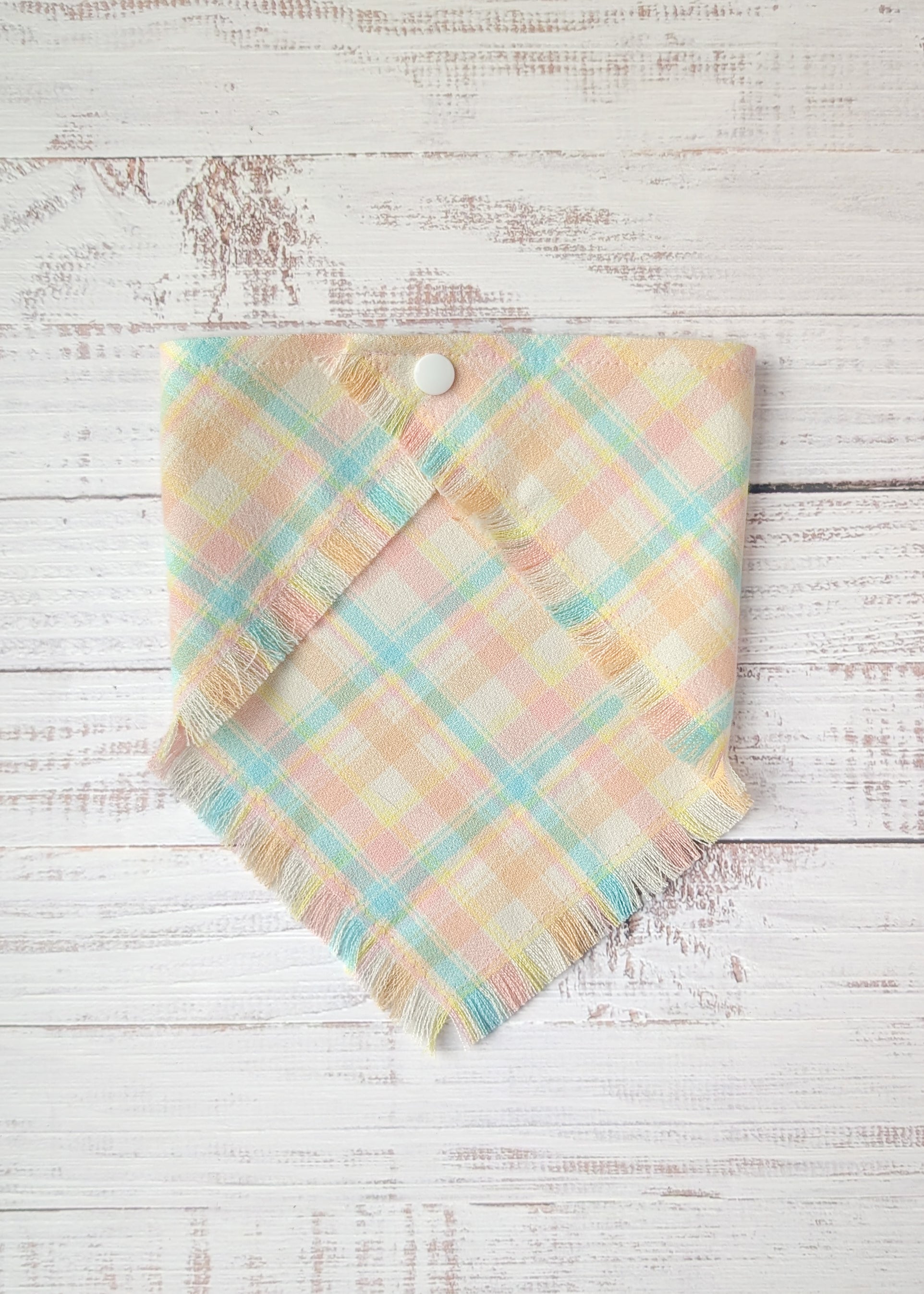 Pastel plaid flannel bandana in yellow, light blue, pink, on a wooden surface