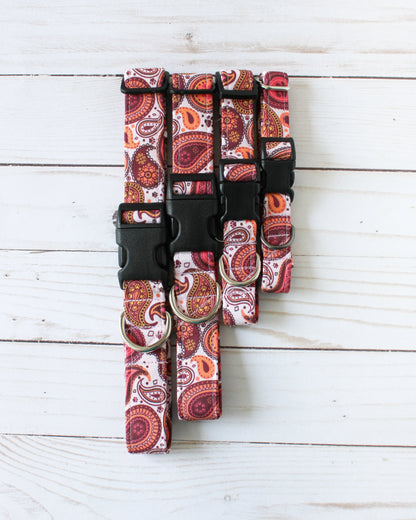 Set of red paisley-patterned Collars on a white wooden surface