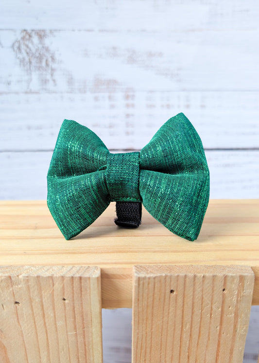 Green bow tie on a wooden surface with a light blue background