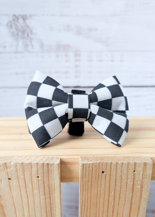 Black and white checkered bow ties on a wooden surface with a light gray background