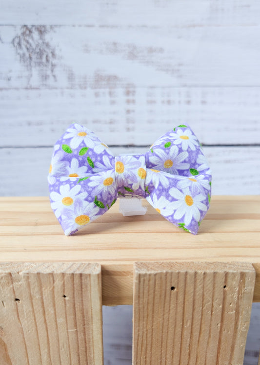 purple daisy dog bow on a wooden surface with a light gray background