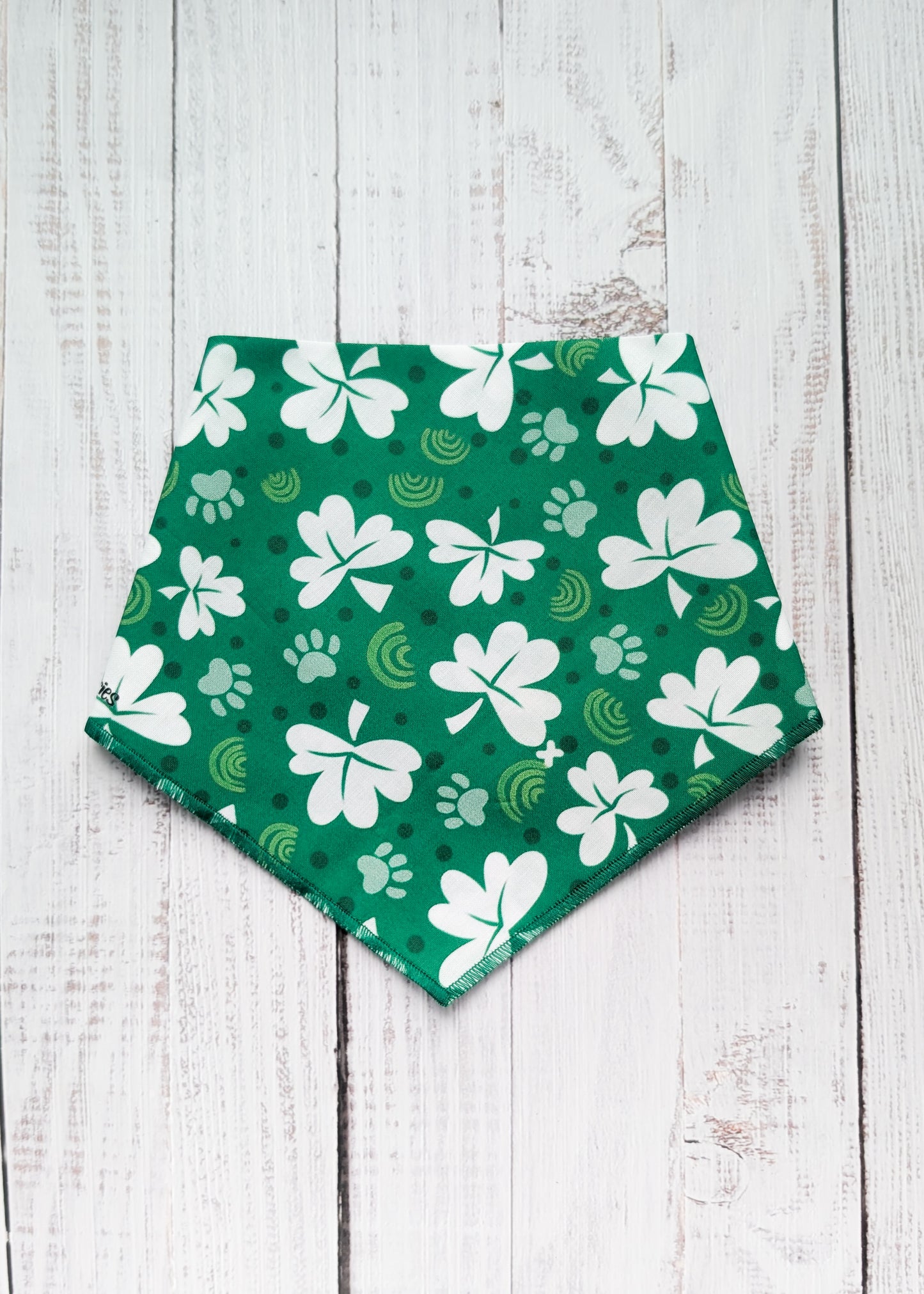 Green bandana with white shamrock patterns on a wooden surface
