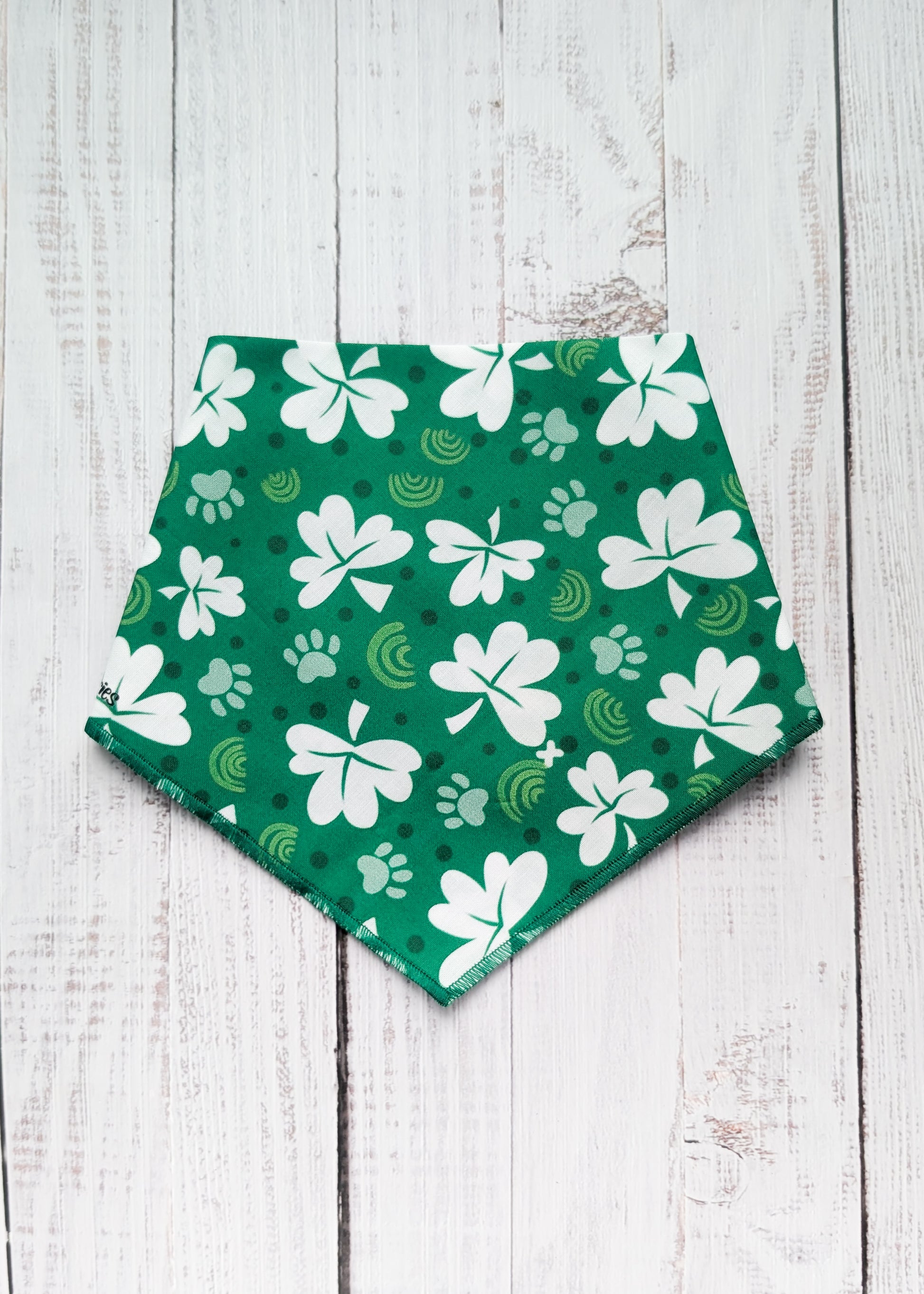 Green bandana with white shamrock patterns on a wooden surface