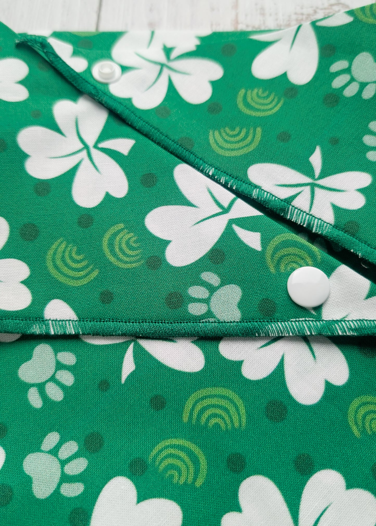 Green bandana with white shamrock patterns on a wooden surface