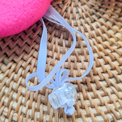 close up of a clear plastic cord lock with the edge of a pink dog beret showing in the upper left