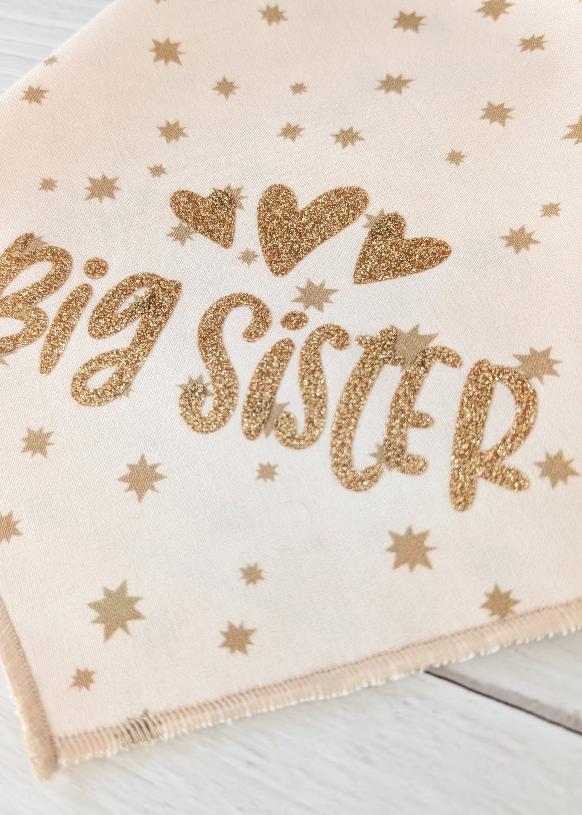 Bandana close up with 'Big Sister' text in gold glitter on a light background