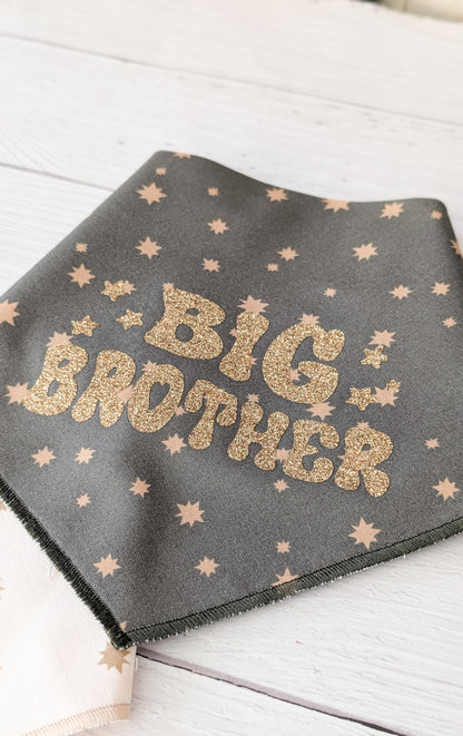 Dark Olive bandana with gold 'Big Brother' text and star patterns on a light wooden surface