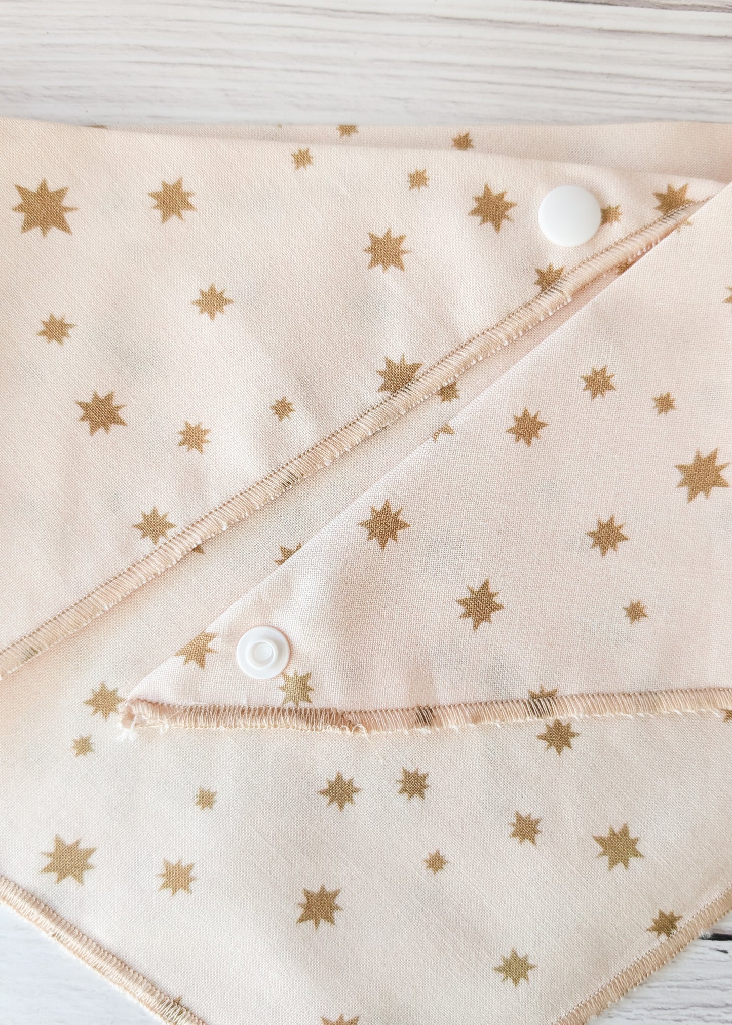 Fabric with gold star pattern and white buttons on a wooden surface