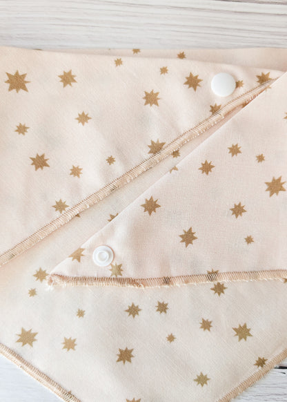 Fabric with gold star pattern and white buttons on a wooden surface