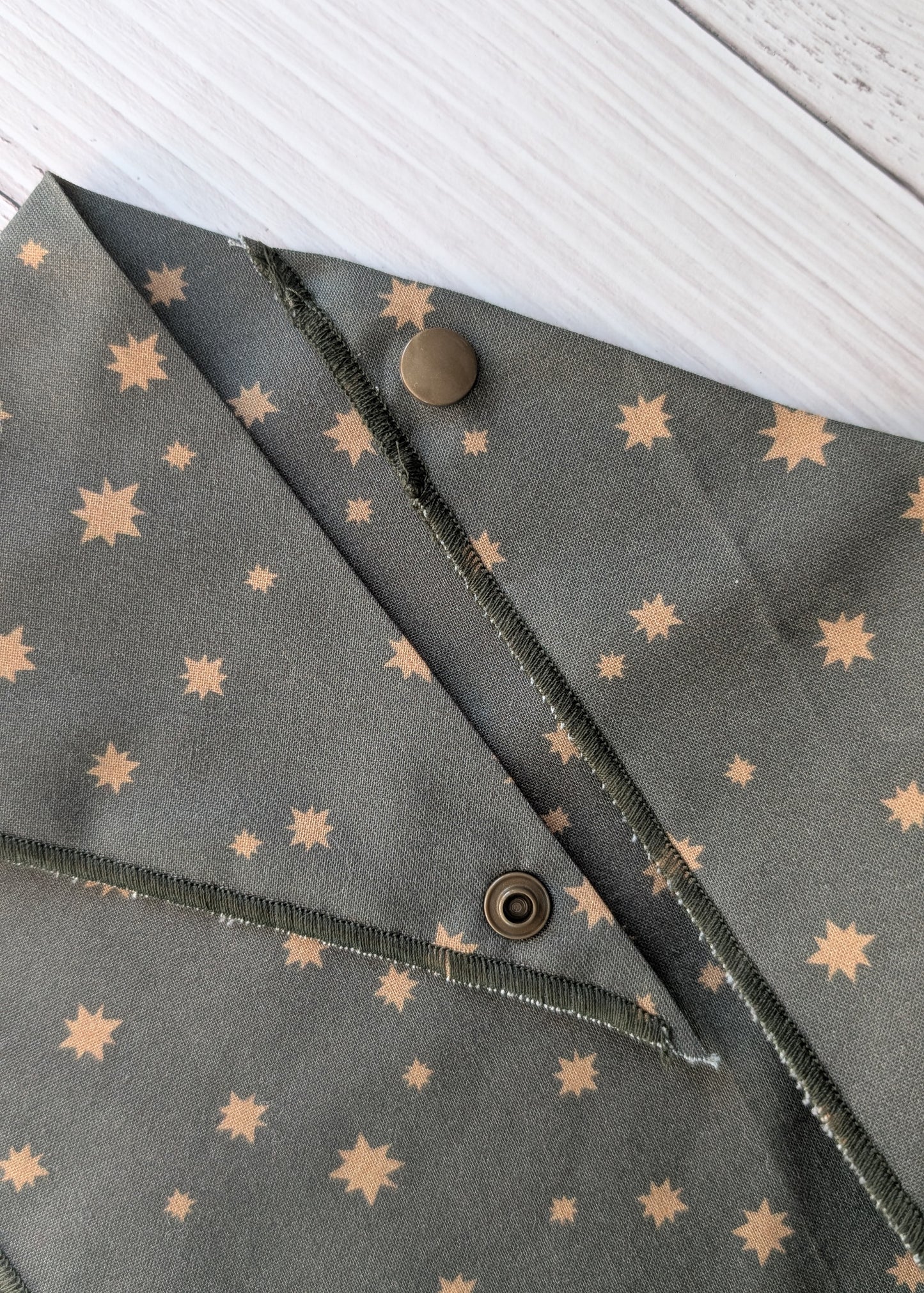 Dark Olive Bandana close up with star patterns and snaps on a white background