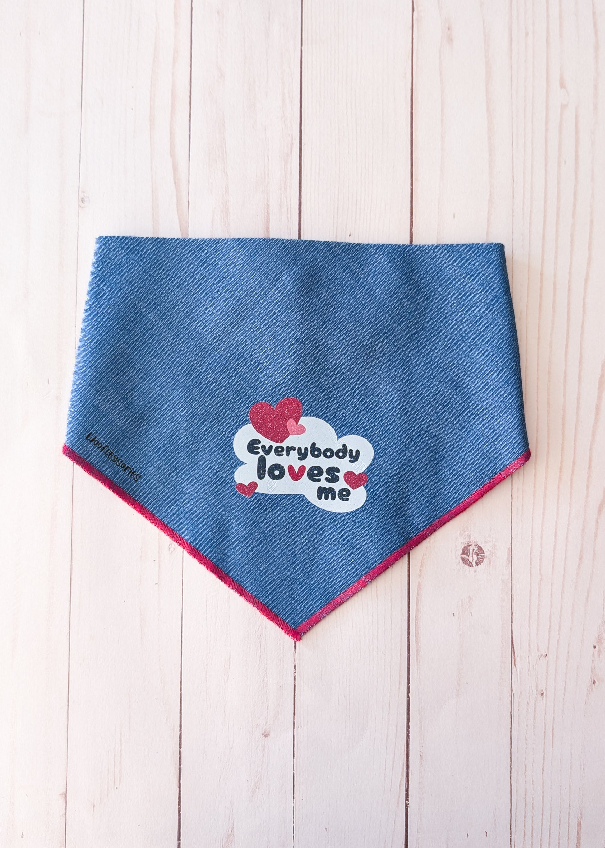 Denim bandana with a quote saying "everybody loves me" on light wood background