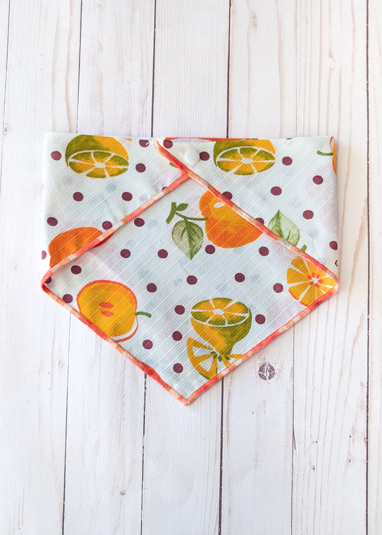 White bandana with fruit theme and polka dots on white wooden background