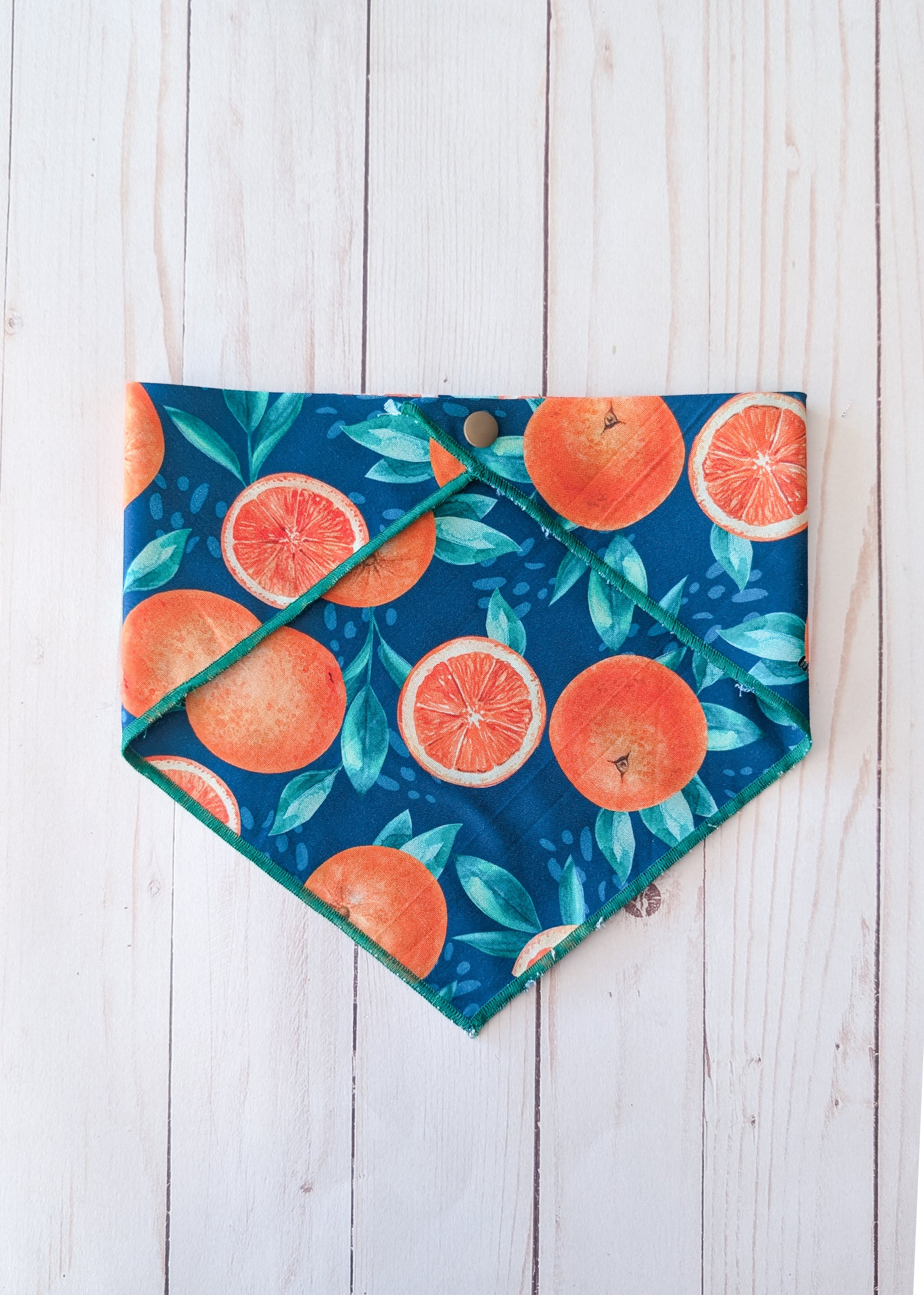 Fruit-themed bandana with oranges and leaves on a wooden surface
