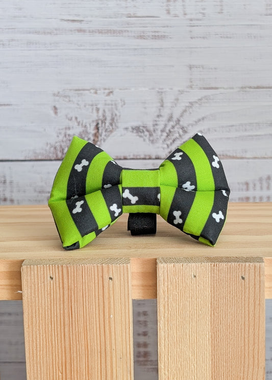 Green and black striped bow tie with bone pattern on a wooden block against a rustic wooden background