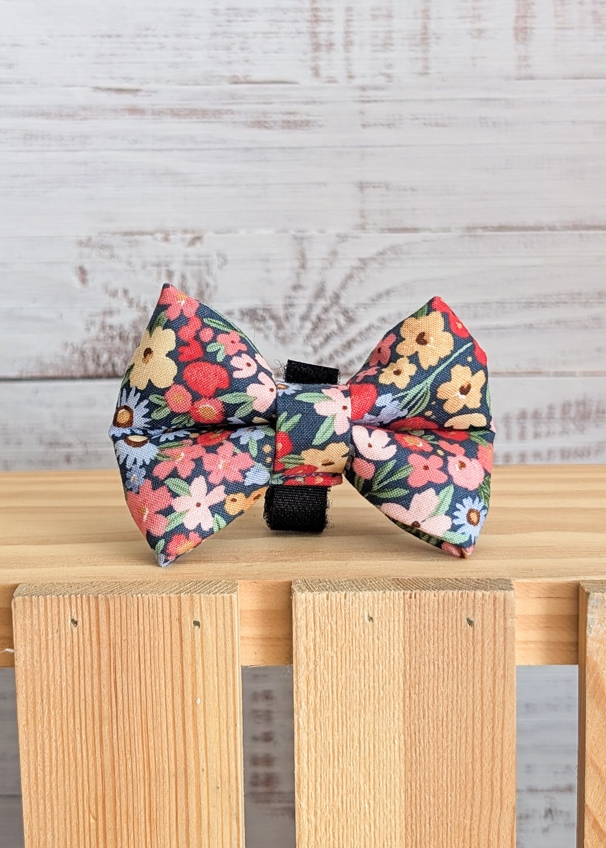 Floral-patterned bow tie on a wooden surface with a light wooden background