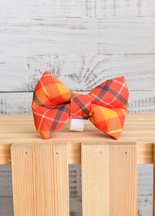 Orange plaid bow tie on a wooden stand and white wood background