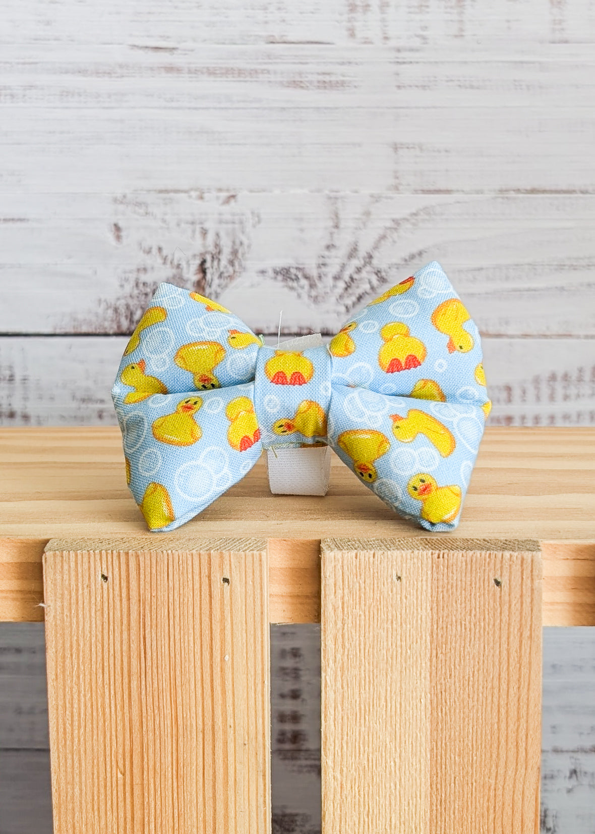 Bow tie with rubber duck pattern on a wooden surface