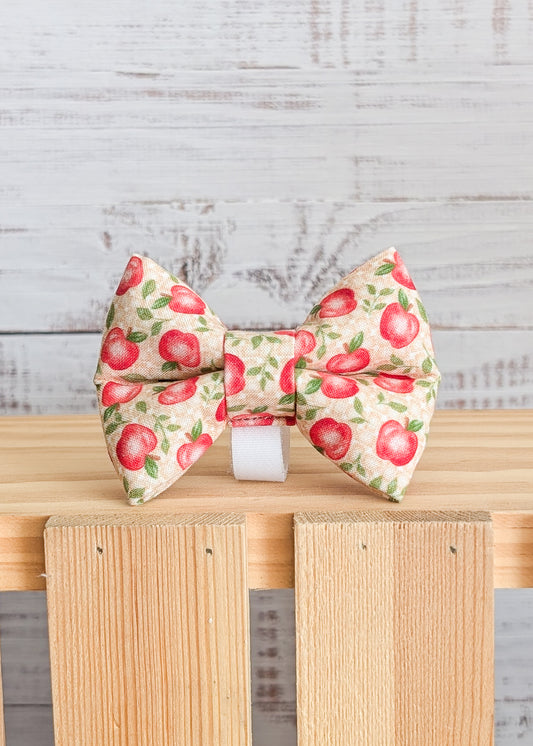 Apple-patterned bow tie on a wooden surface with a light gray background