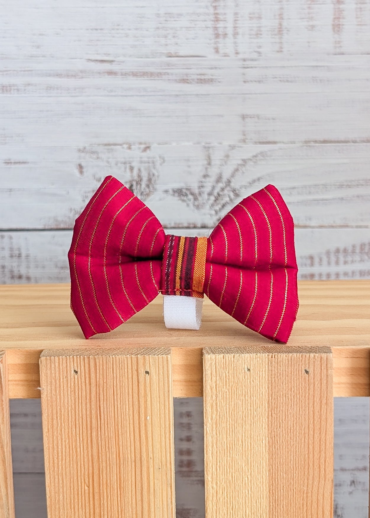 Red striped bow tie on a wooden block with a light gray background