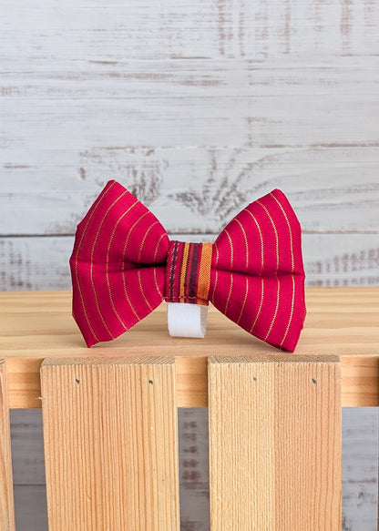 Red striped bow tie on a wooden block with a light gray background