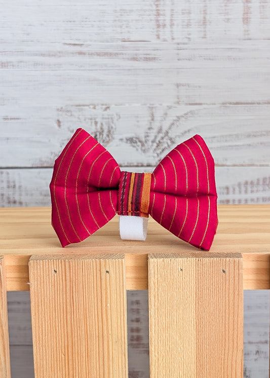 Red striped bow tie on a wooden block with a light gray background