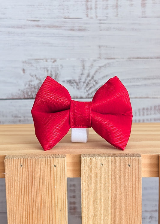 Red bow on a wooden block with a light gray background