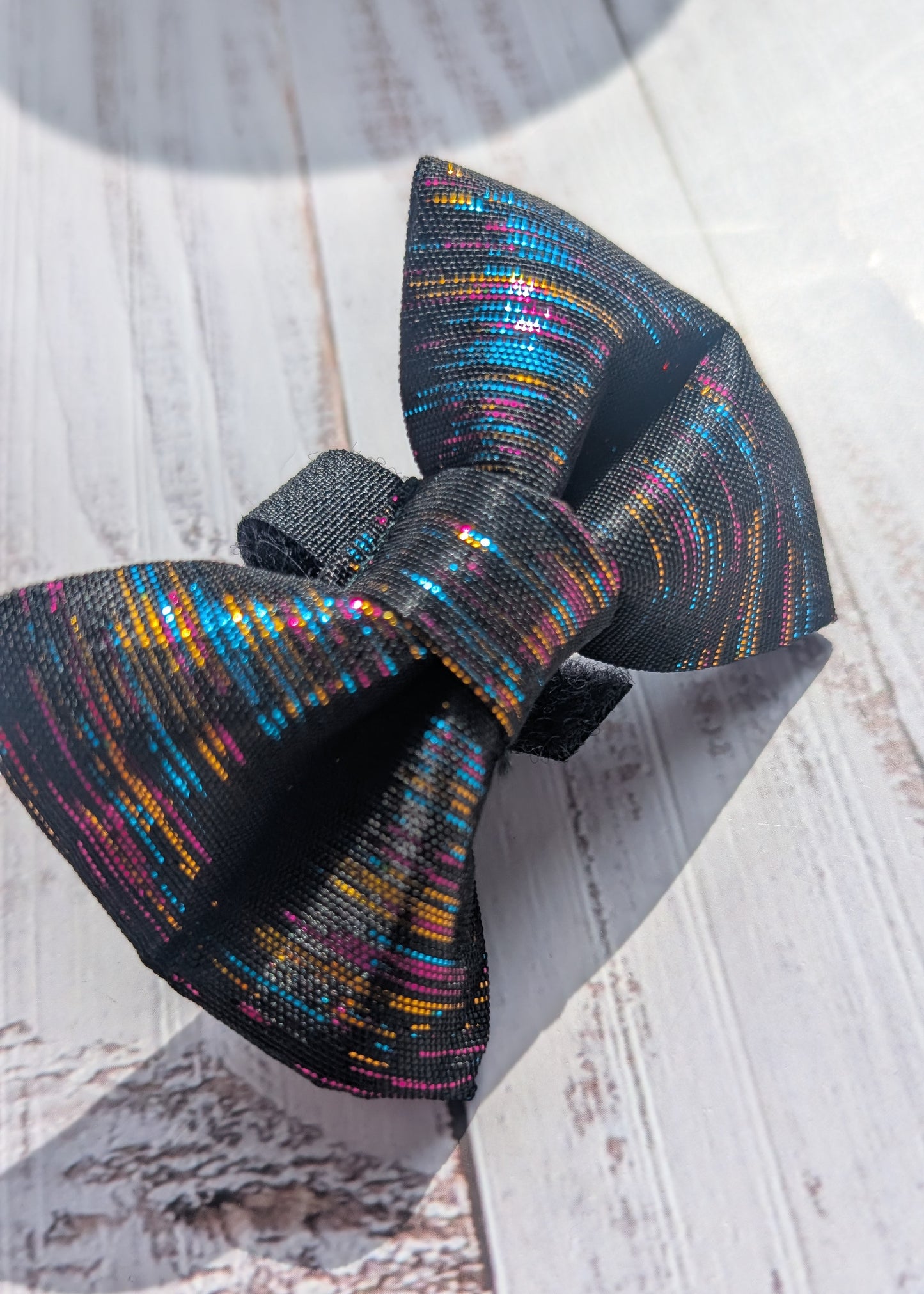 black bow tie with multicolor metallic thread on a wooden background