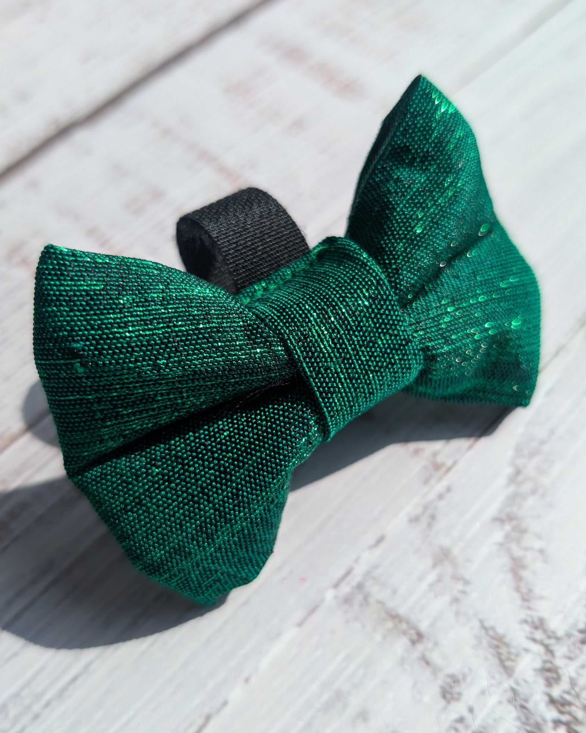 Green bow tie on a wooden surface with a light blue background