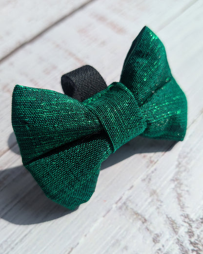 Green bow tie on a wooden surface with a light blue background