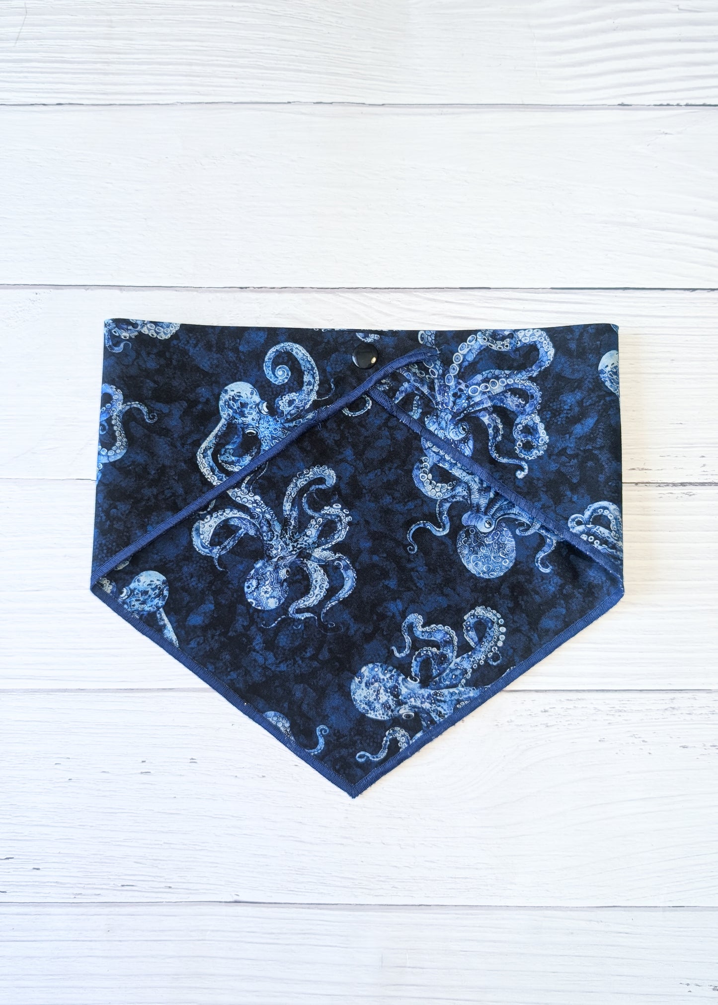 Blue bandana with white octopus pattern on a white wooden surface