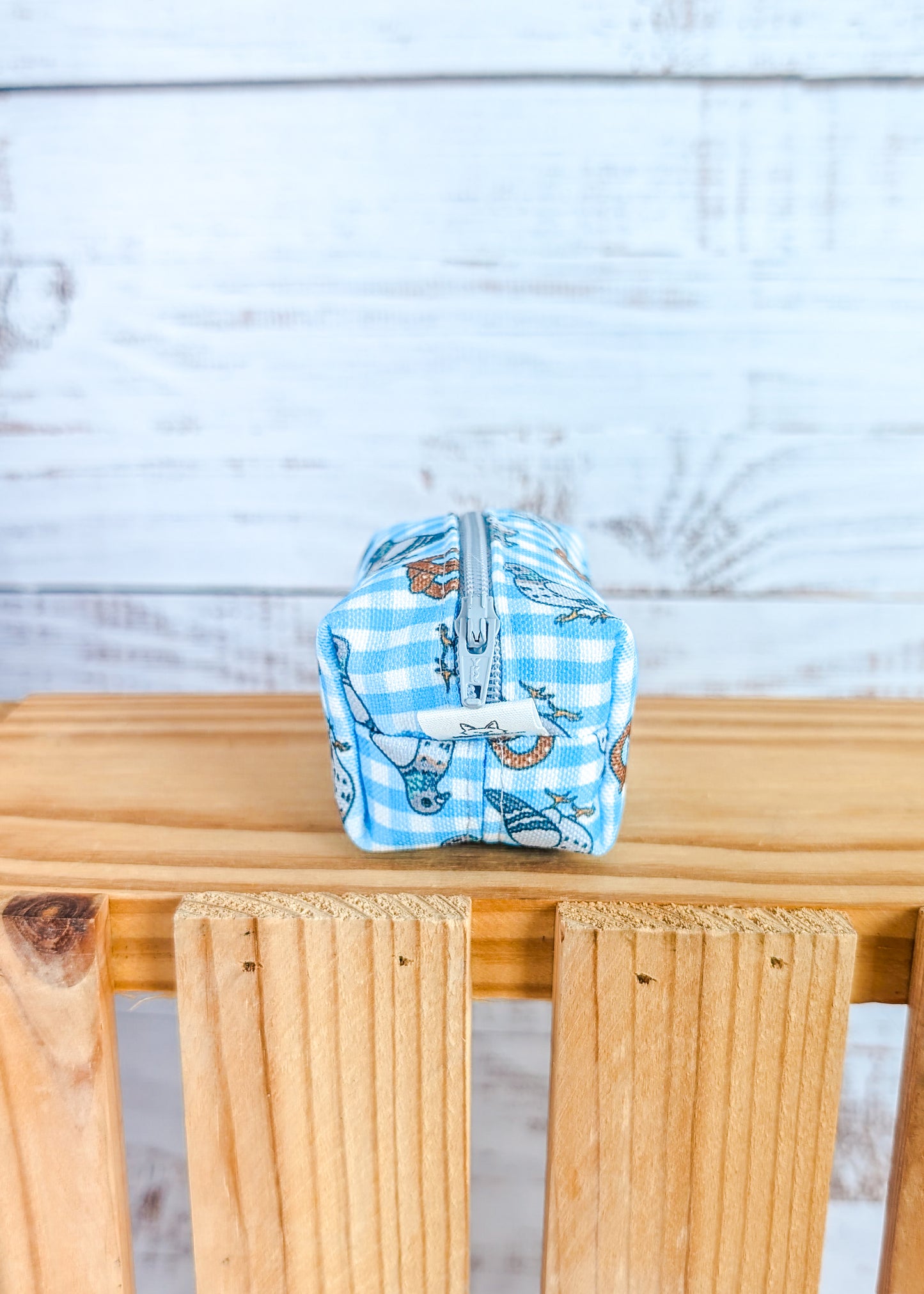 Small pouch with pigeon and pretzel design on a wooden surface against a light wooden panel background