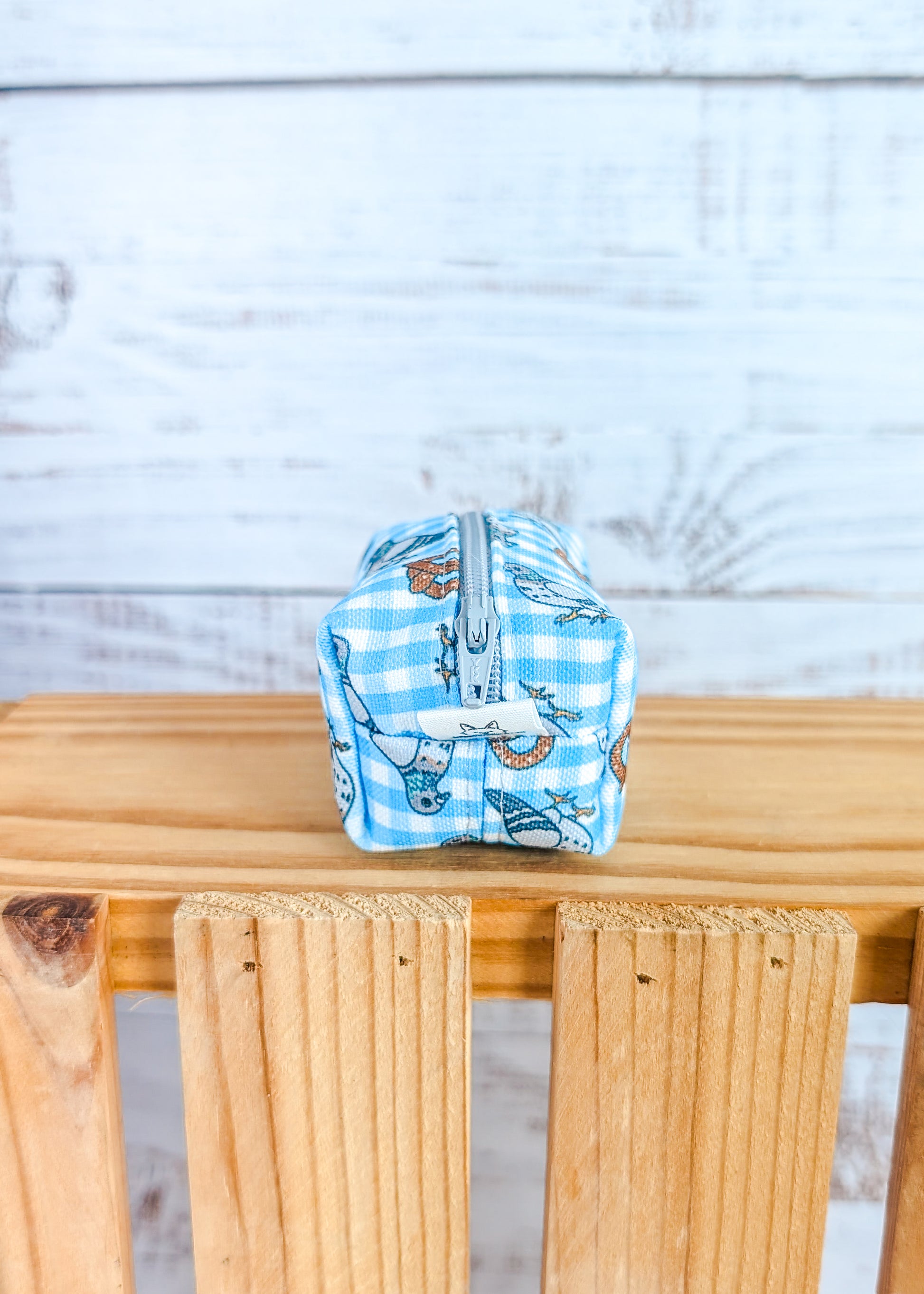 Small pouch with pigeon and pretzel design on a wooden surface against a light wooden panel background