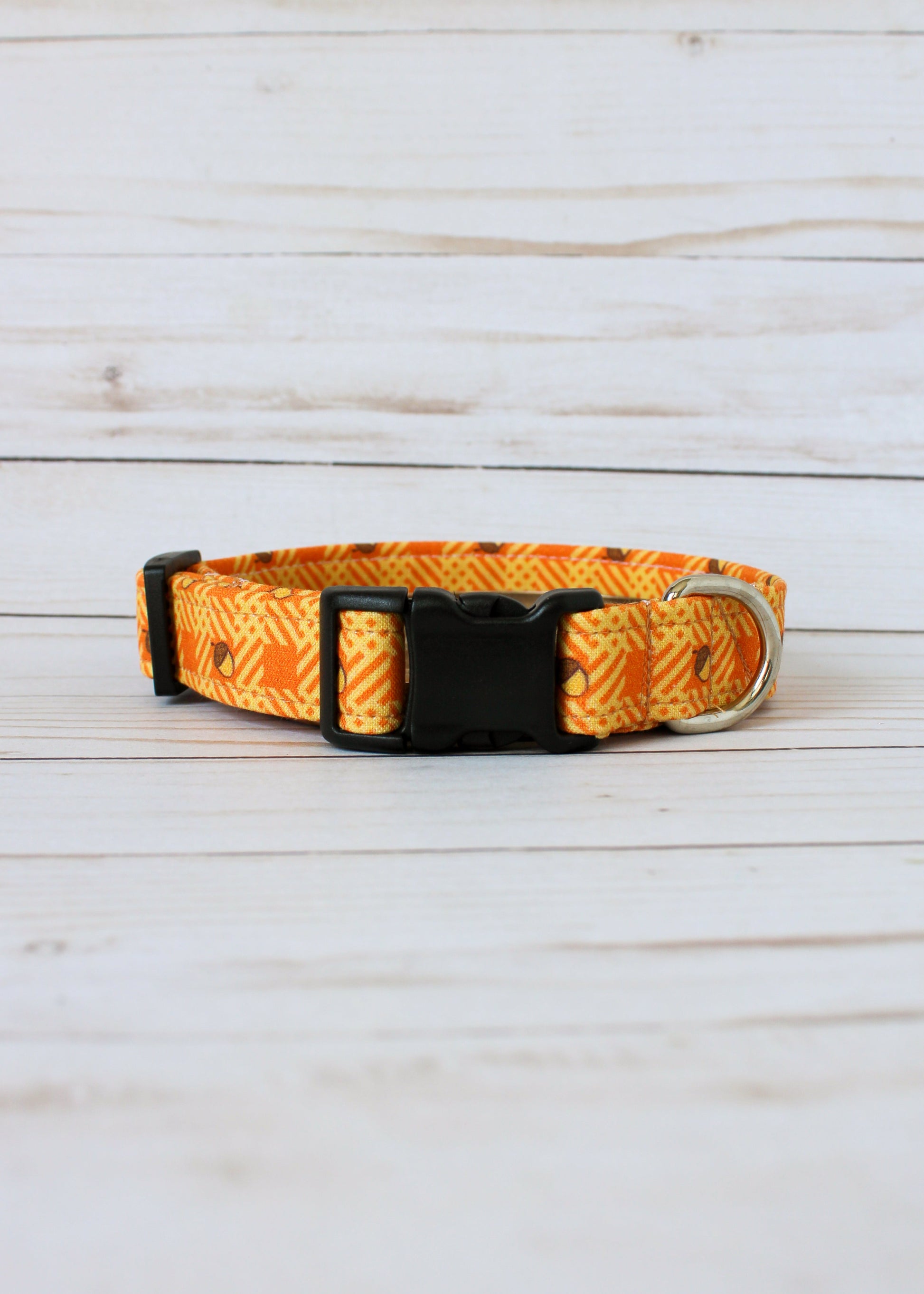 Dog collar with orange and yellow pattern with acorns on a light wooden surface