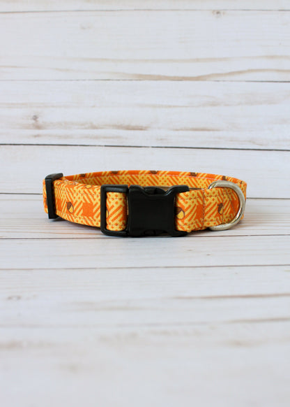 Dog collar with orange and yellow pattern with acorns on a light wooden surface