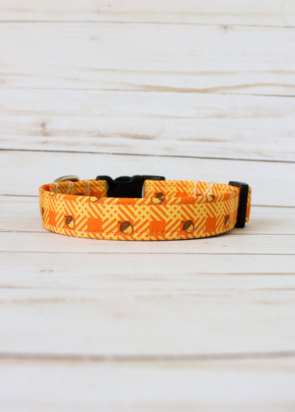 Dog collar with orange and yellow pattern with acorns on a light wooden surface