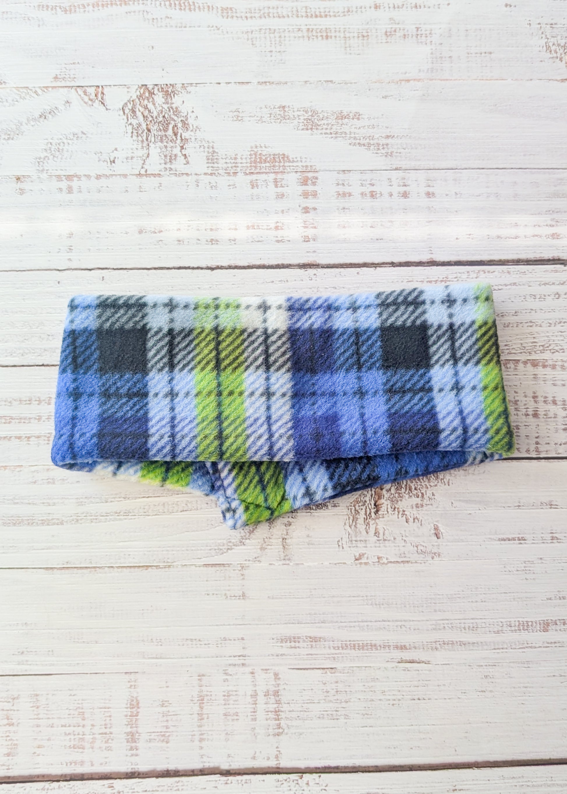 Blue, lime, white, black plaid fleece scarf on a wooden background back view