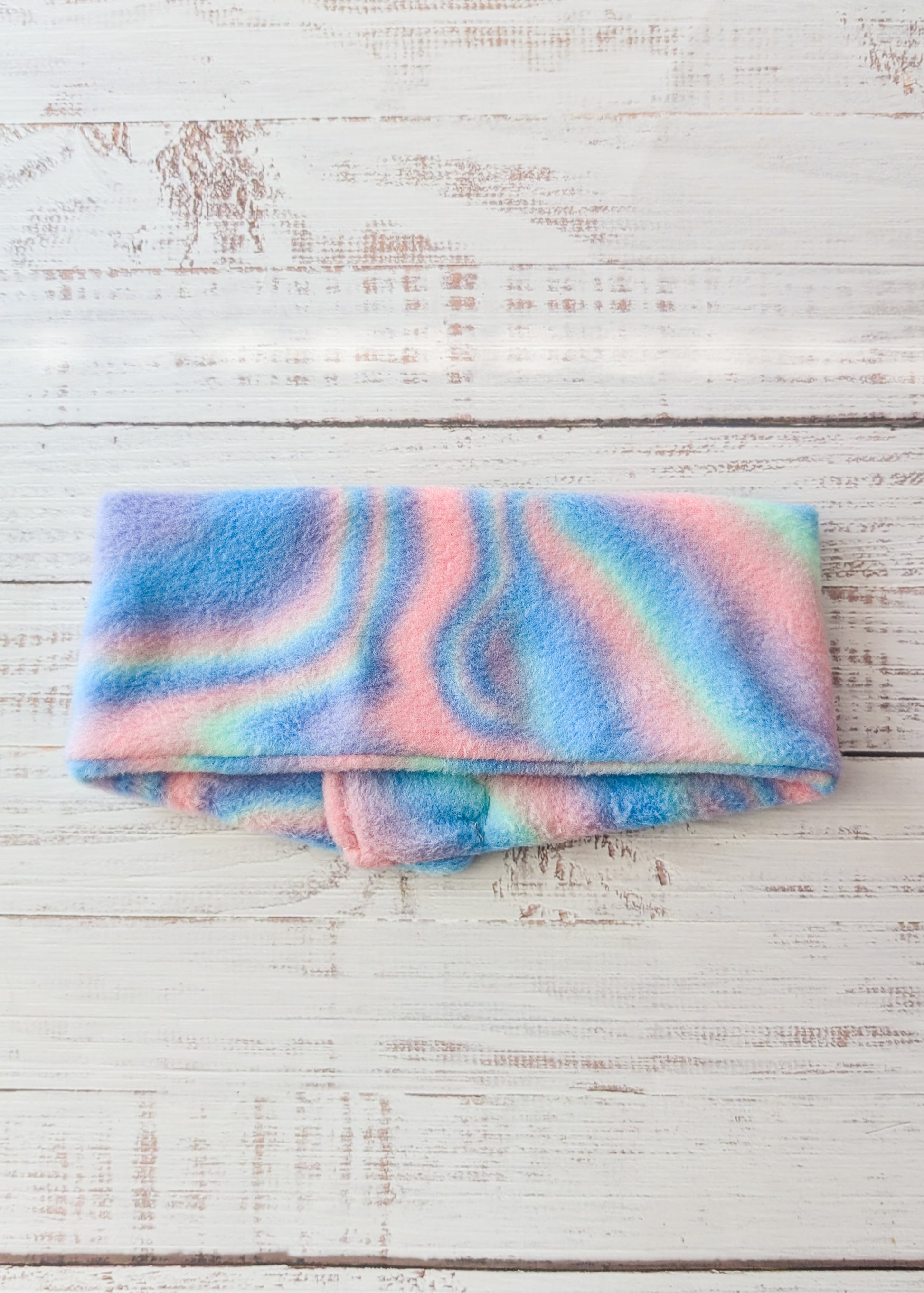 Pastel tie-dye fleece dog scarf on a wooden surface back view